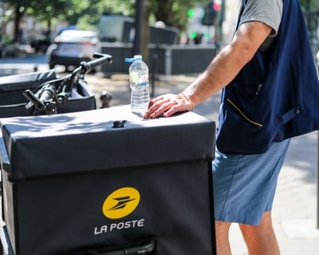 A postal worker drinks water during a delivery round in Paris, France.