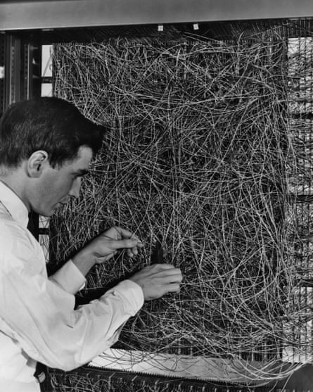 A man adjusting a dense wiring network.