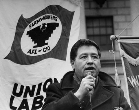 A black-and-white image of a man in a pea coat holding a microphone outdoors, in front of a banner with the UFW/AFL-CIO logo.