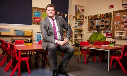Martyn Oliver sitting on a desk in a primary school classroom