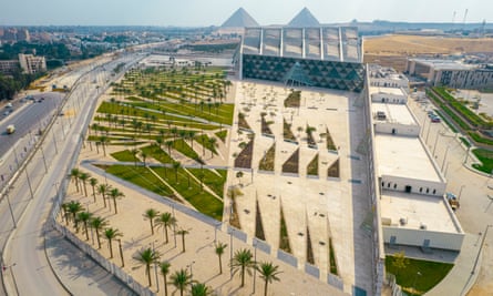 The museum in parkland next to a road with the pyramids in the background