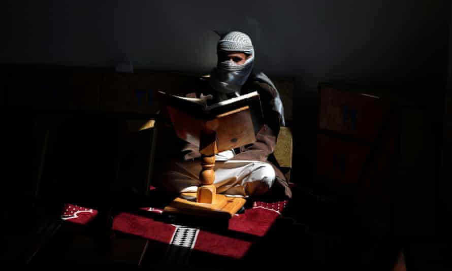 A man covers his face with a shawl to read the Qur’an at a mosque in the Yemeni capital, Sana’a