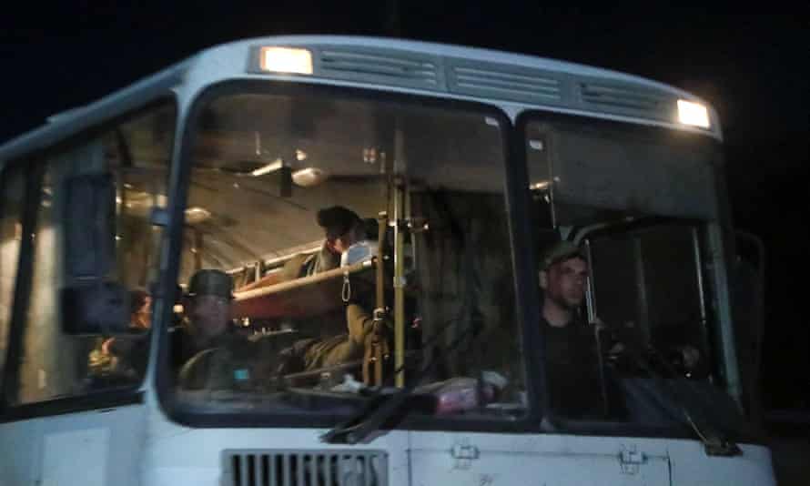A bus carrying Ukrainian soldiers from the Azovstal steel mill drives away under the escort of the pro-Russian military.