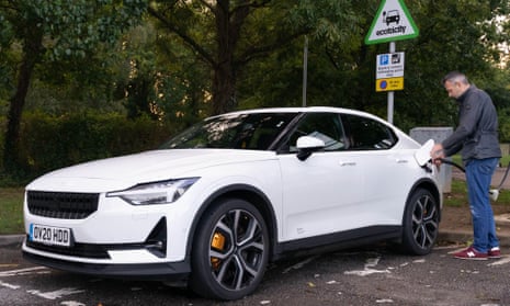 Man charging an electric vehicle in a public EV recharging bay