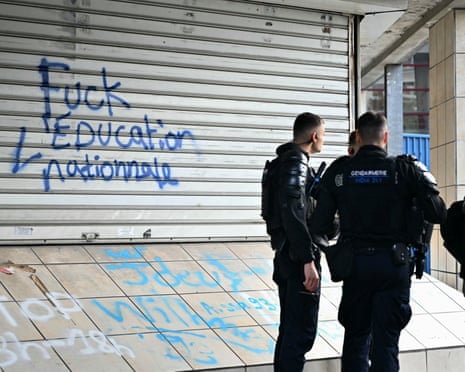 Anti-riot police officers stand guard next as protesting students carry out blockading action outside the vocational high school of image and sound Suger, in Saint-Denis, northern Paris.