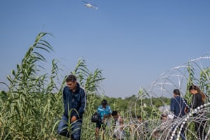 People from El Salvador walk through brush along the banks of the Rio Grande in Texas after crossing into the US