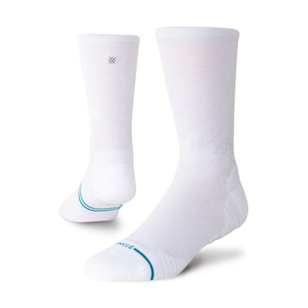 A pair of Stance crew socks in white. There is a turquoise line across the foot from the ball of the toe.
