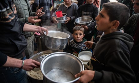 Displaced Syrians wait for hot meal in Idlib, Syria, last month.