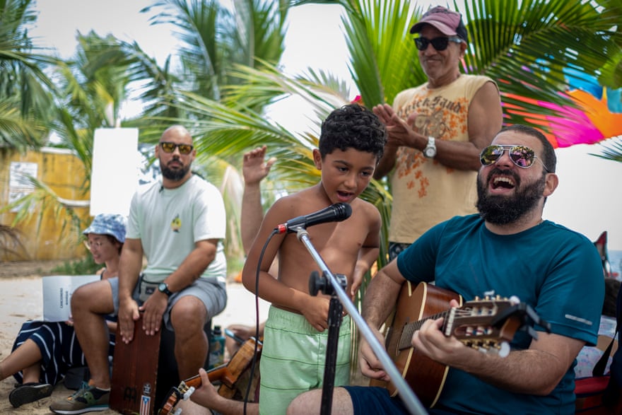 People gather to sing and play music during a party protest at Los Almendros beach.