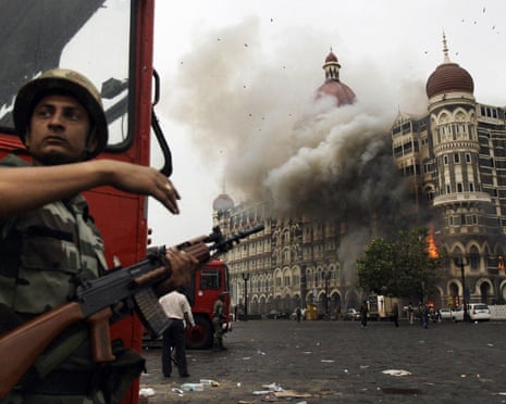An Indian soldier takes cover as the Taj Mahal hotel burns during a gun battle with militants in November 2008.