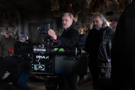 Christopher Nolan looks into a monitor surrounded by crew