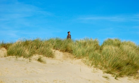 Peace and solitude: a woman walking in the sand dunes at Camber Sands, East Sussex.