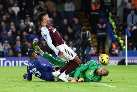 Ollie Watkins watches the ball head towards the net after ricocheting from him off the floored Robert Sánchez
