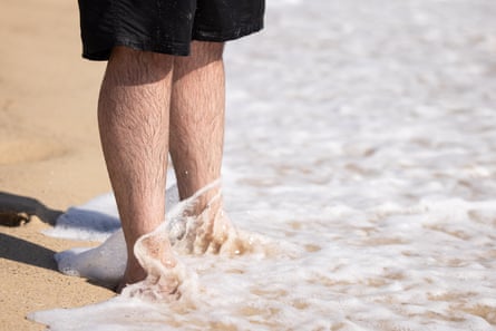 Mostafa Rachwani stands at the beach shoreline as water rushes over his feet