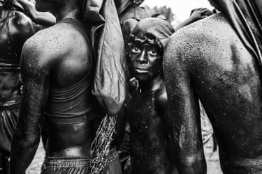 A young boy looks at the lens while sandwiched between two older people’s shoulders