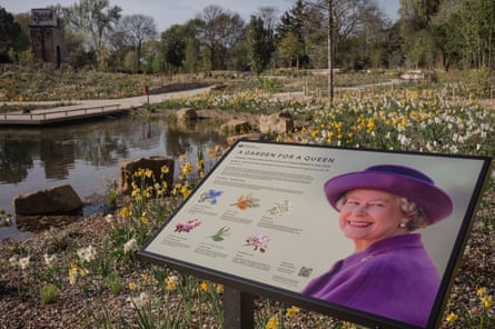 An information board shows various flowers next to a photo of the late Queen Elizabeth II, next to a pond surrounded by flowers.