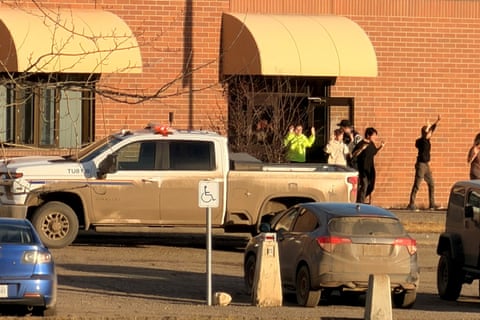 students walk out of a building with their hands raised