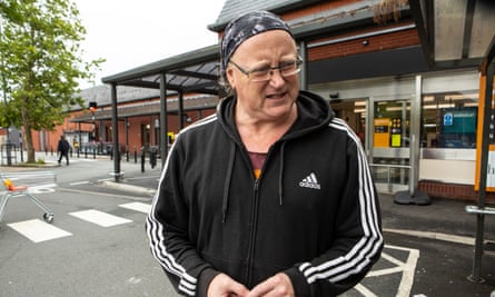 Philip Jones, wearing black Adidas tracksuit top with white stripes and a bandana tied around his head, photographed in a supermarket car park