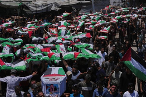 Palestinians carry the flag-draped bodies through Gaza City.