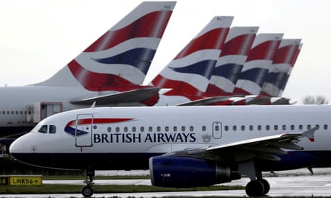 A British Airways plane taxis past tail fins of parked aircraft at Heathrow airport in London