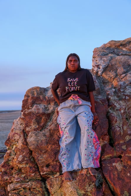 A woman standing on rocks wearing a T-shirt that says ‘Save Lee Point’