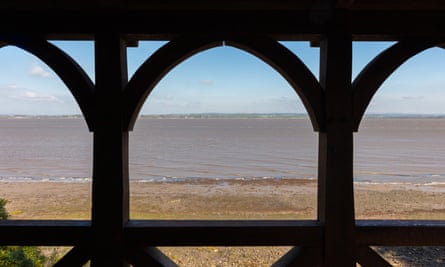 Sea and coast in the distance seen through the shaded arches of a wooden structure
