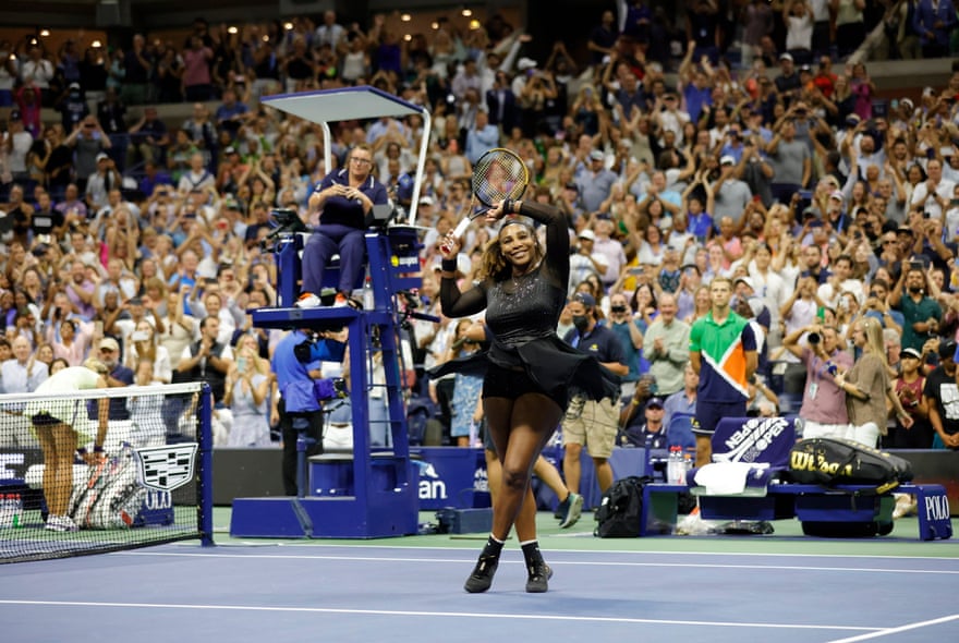 Serena Williams lève sa raquette et son bras vers la foule alors qu'elle se tient sur le terrain après sa victoire