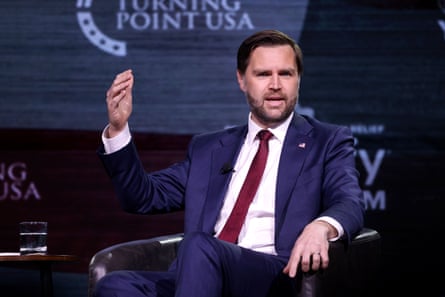 JD Vance gestures as he speaks on a stage while sitting down