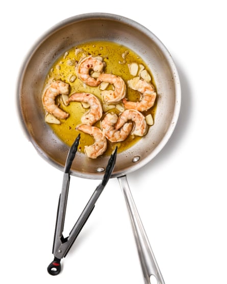 Prawns in a frying pan with tongs