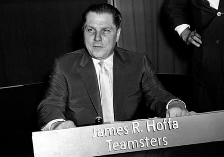 A man sits behind a placard naming him as James R Hoffa with the Teamsters.