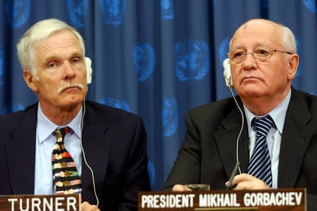 two men in suits sit side by side each with an earphone to hear translation