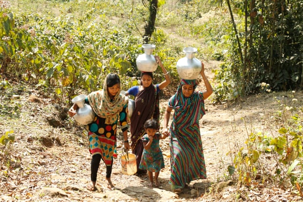 Women return home after collecting drinking water from a ringwell at the Sreepur tea estate, Sylhet. They have to cross a dangerous highway to reach the water spot.