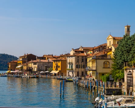 Historic buildings painted different shades of yellow and with red roof tiles lined up along the waterfront