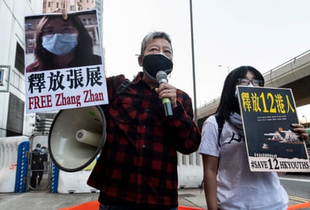 An activist holds a sign reading ‘free Zhang Zhan’ next to another person with a sign reading ‘save 12 HK youths’