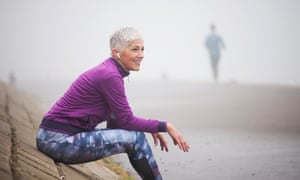 Beautiful mature woman jogging through fog in early autumn day