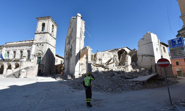 A firefighter stands in front of the destroyed basilica of San Benedetto in the historic centre of Norcia one day after the quake hit.