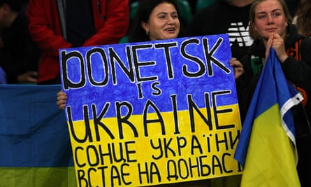 Woman holding a sign saying ‘Donetsk is Ukraine’ then words underneath in cyrillic