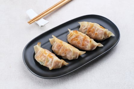 A dark plate with four fried mandu dumplings on it