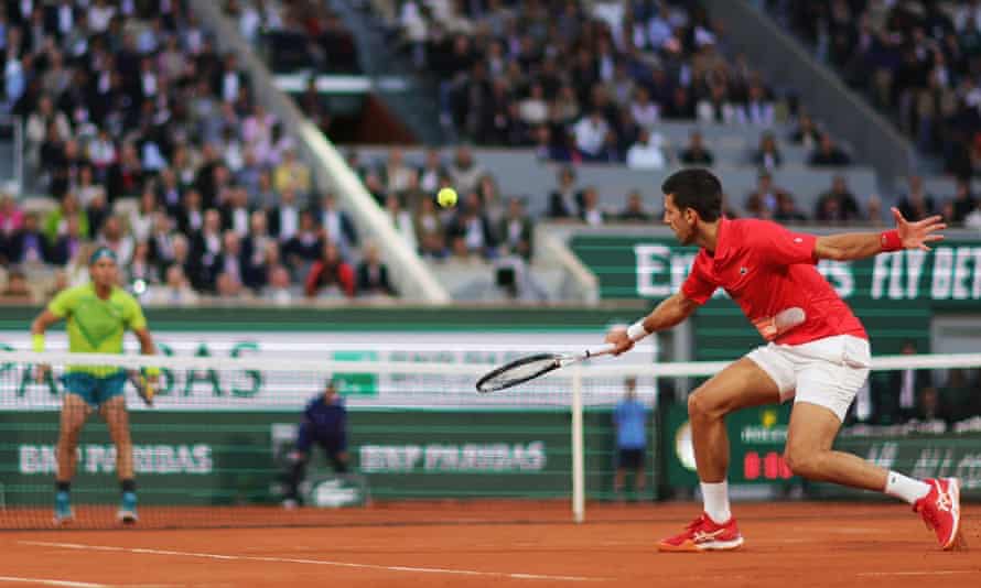 Novak Djokovic plays a backhand as Rafael Nadal readies himself for a return.