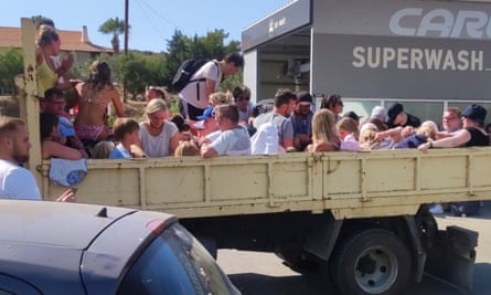 Tourists in the back of a lorry being evacuated.