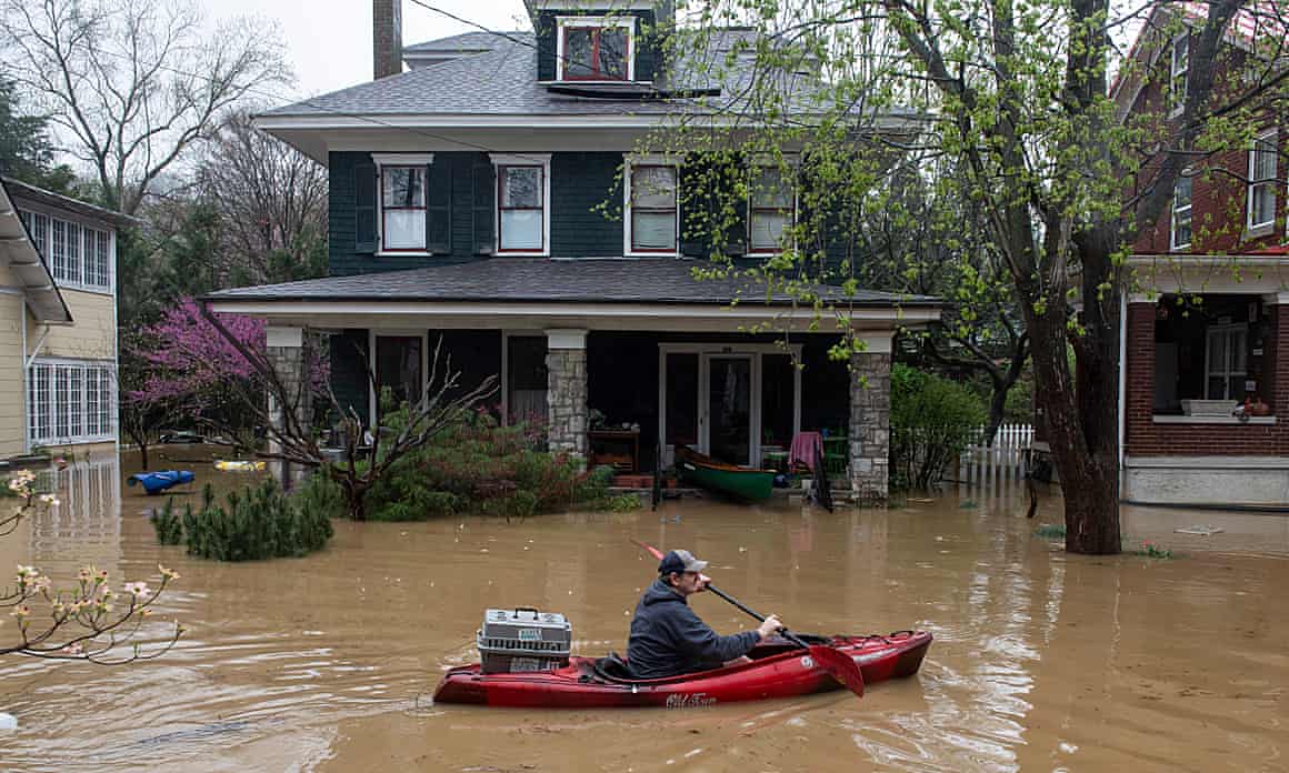 John Clayton, 56, carries his cat in a kayak as the Kentucky River begins to flood his house in Frankfort, Kentucky.
