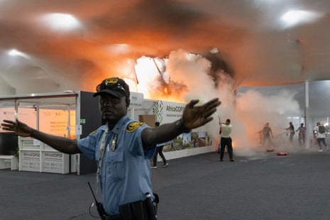 A security guard gestures as people use fire extinguishers to put out a fire at Cop30 in Belem