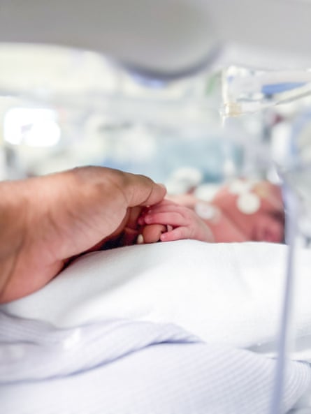 A newborn hand holds an adult finger.