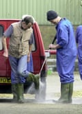 To prevent the spread of foot and mouth, worker s have their boots sprayed before entering Orchard farm in west Horndon, Essex, 21 February 2001.