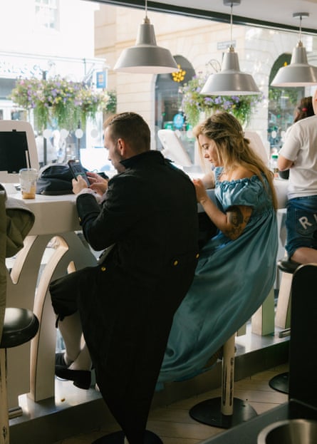 A couple of festivalgoers in period costumes sit in the window of a McDonald’s