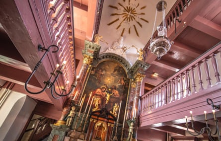 Interior of old church painted pink with an altar below and balcony above