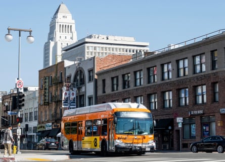 An orange bus drives along a street