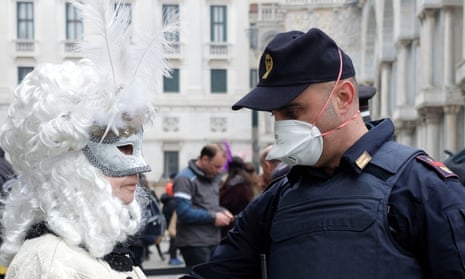A police officer wearing a protective face mask stands next to a masked carnival reveller at Venice Carnival, which the last two days of, as well as Sunday night’s festivities, have been cancelled because of an outbreak of coronavirus, in Venice, Italy February 23, 2020. REUTERS/Manuel Silvestri