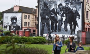 A family walks past a mural depicting a scene from Bloody Sunday in Londonderry, Northern Ireland