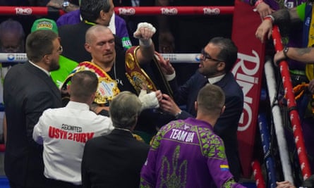 Oleksandr Usyk carries his title belts as he celebrates after winning the WBA, WBO, and WBC world heavyweight title fight against Tyson Fury
